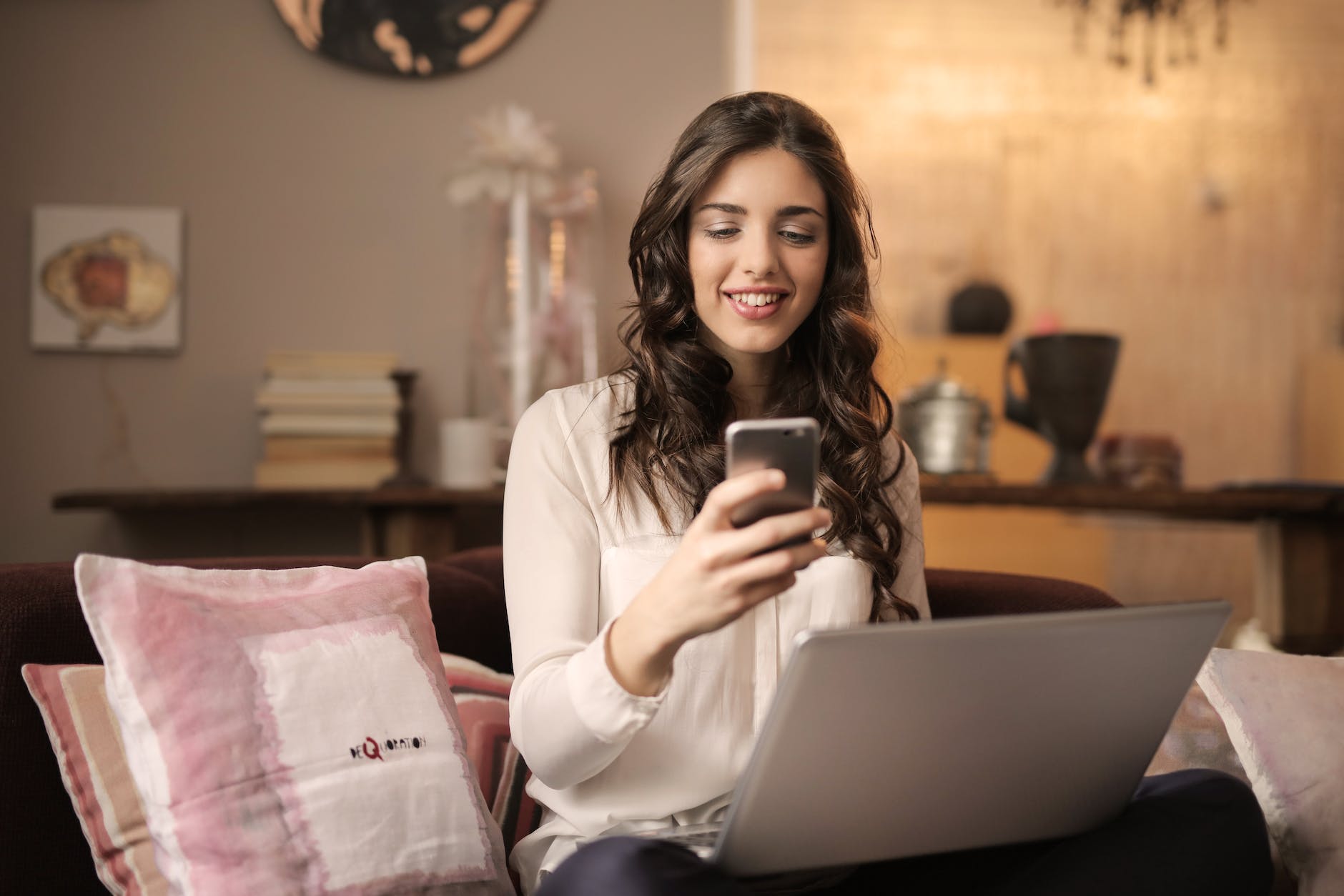 Mujer usando su teléfono frente a una laptop