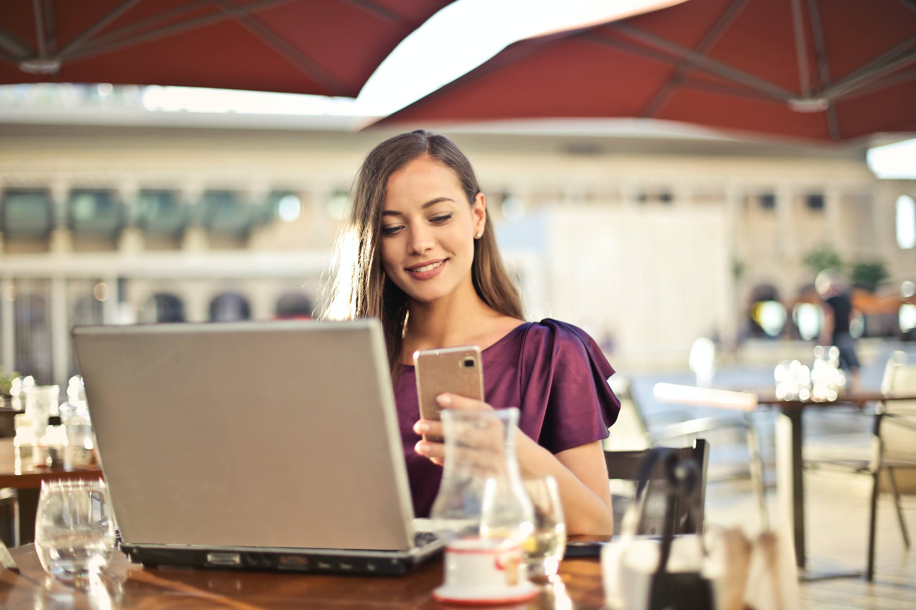 Mujer con teléfono y laptop en una cafetería